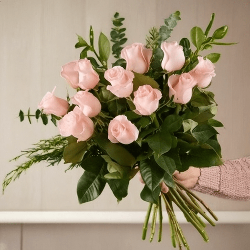 Dozen light pink roses bouquet with greens and fillers.