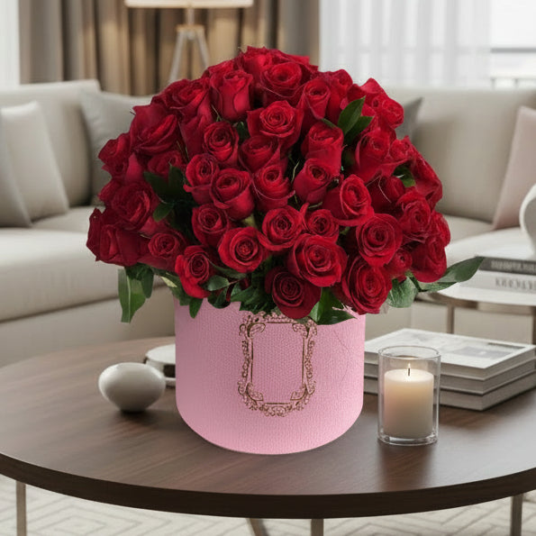 red roses in a pink hat box set in a wooden floor.