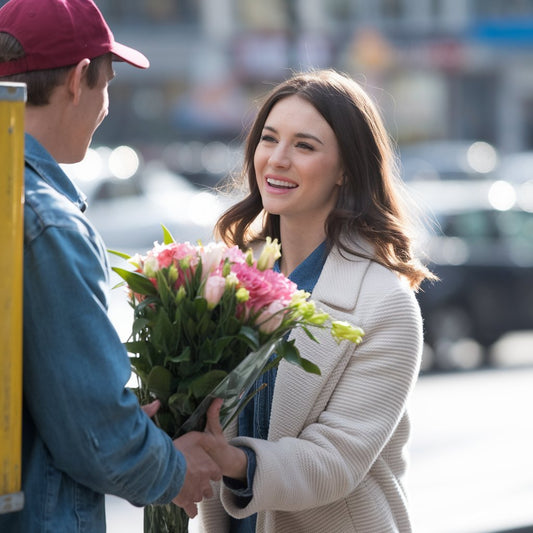 A delivery guy giving flowers to a young woman.