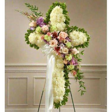 Sympathy cross with white flowers and mixed colors across the center located at a funeral home.