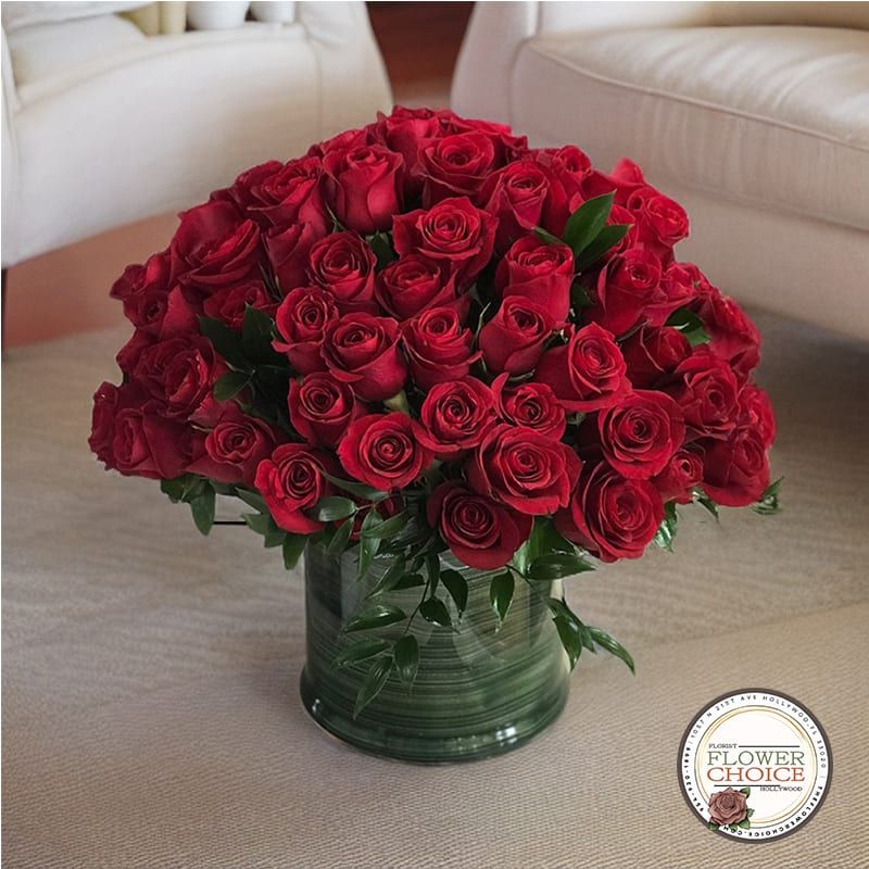 A large bouquet of red roses in a green vase, placed on a light-colored surface with a logo in the corner saying 'Flower Choice'.