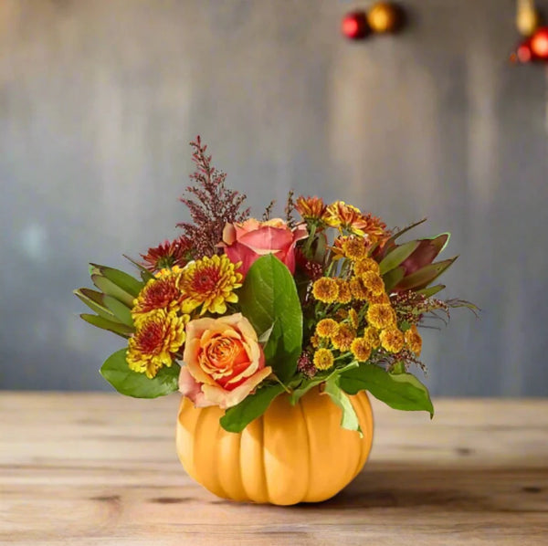 Autumn Pumpkin vase with fall flowers arranged on a table.