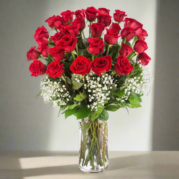 A bouquet of red roses and white flowers in a clear glass vase.