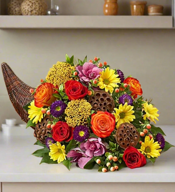 A mixed Autumn Floral arrangement cornucopia, With lots of yellow orange and brown flowers and ornaments.