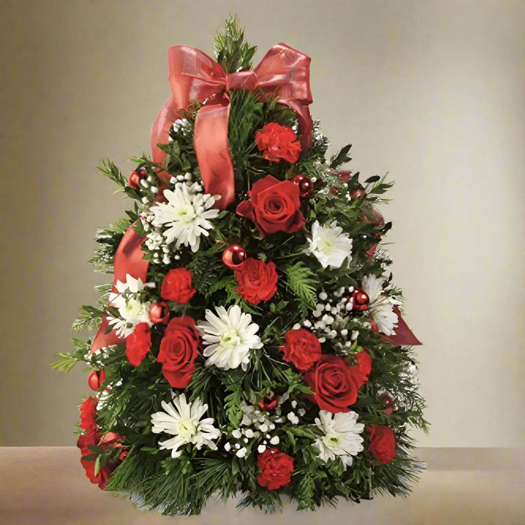 Shaped like a festive Christmas tree arrangement, this unique design features fresh holiday greens, classic red roses, delicate white blooms, and seasonal fillers.