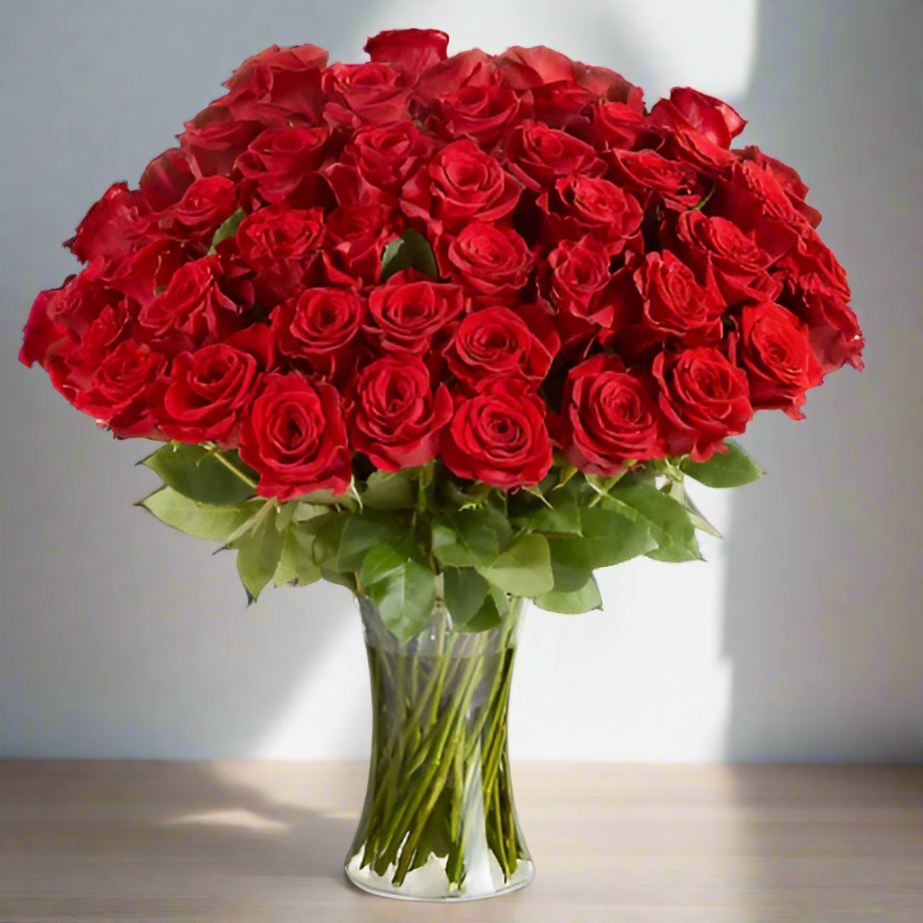 50 red roses arrange in a tall clear vase.