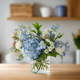 Blue and white floral arrangement with blue hydrangeas and white roses with fillers