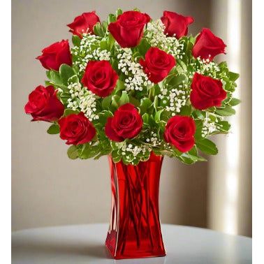 A bouquet of red roses with white baby's breath in a red vase.