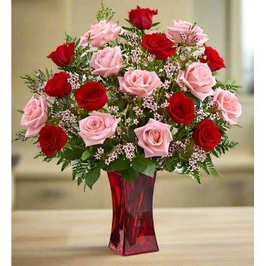 Bouquet of red and pink roses in a red vase on a table.