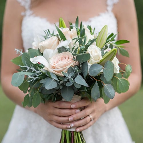 Bouquet of flowers held by a person in a white dress.