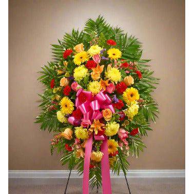 Bright Standing Spray with red and yellow flowers, standing next to the wall