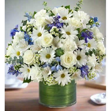 arrangement of blue and white roses, delphinium, alstroemeria, carnations, and daisy poms is a heartfelt way to remember a loved one in times of sorrow.