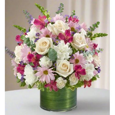 A bouquet of mixed flowers in a round green vase.