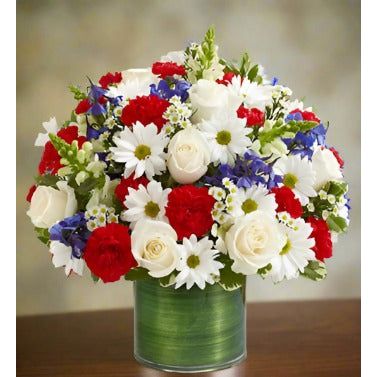 Bouquet of white roses, red carnations, white daisies, and blue flowers in a green vase.