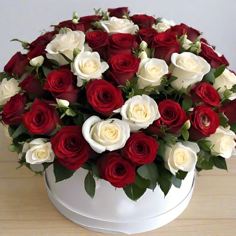 Bouquet of red and white roses in a white round box.