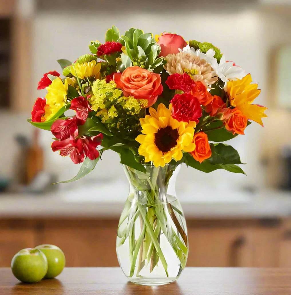 Fall floral arrangement wit orange roses, carnations and sunflowers.