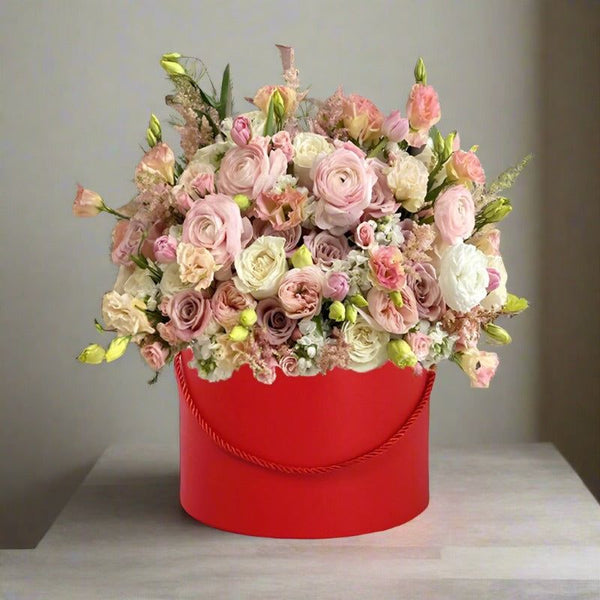 A bouquet of various pink and white flowers in a red container.