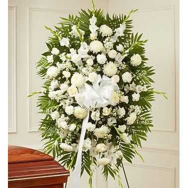 All white standing spray with roses carnations poms and other flowers with greens.