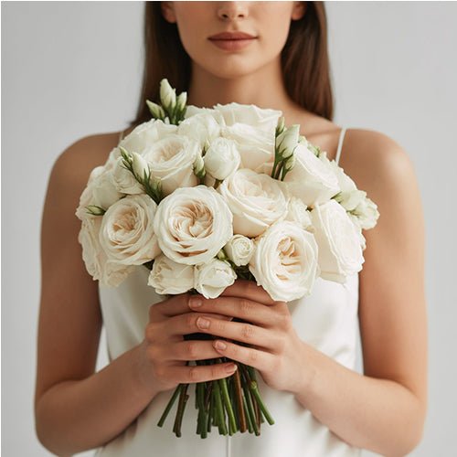 Woman holding a bouquet of white roses against a neutral background