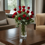 A vase with a bouquet of red roses placed on a wooden table in a living room.