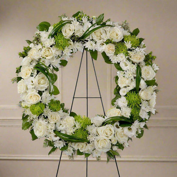 white and green wreath with white flowers like roses, hydrangeas and more.