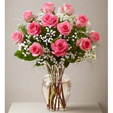 Bouquet of pink roses and white baby's breath in a clear glass vase.