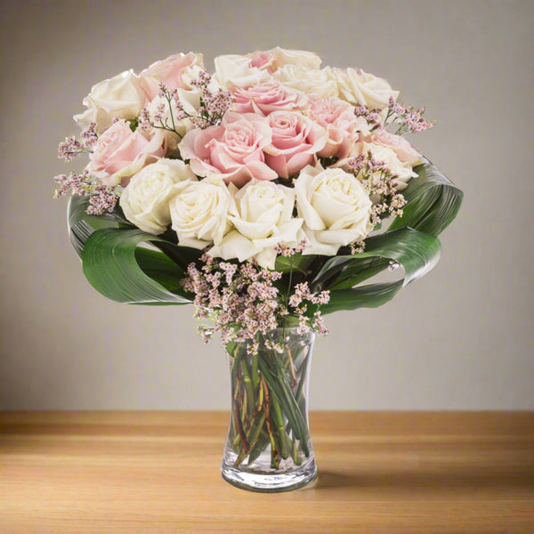 Bouquet of white and pink roses in a glass vase.