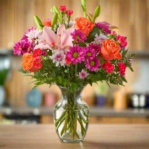 Vase with a bouquet of colorful flowers on a wooden table