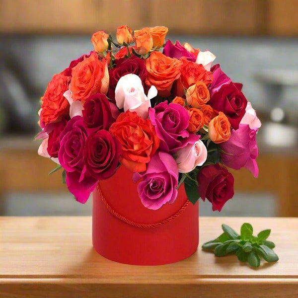 Bouquet of mixed colorful roses in a red vase on a wooden table.