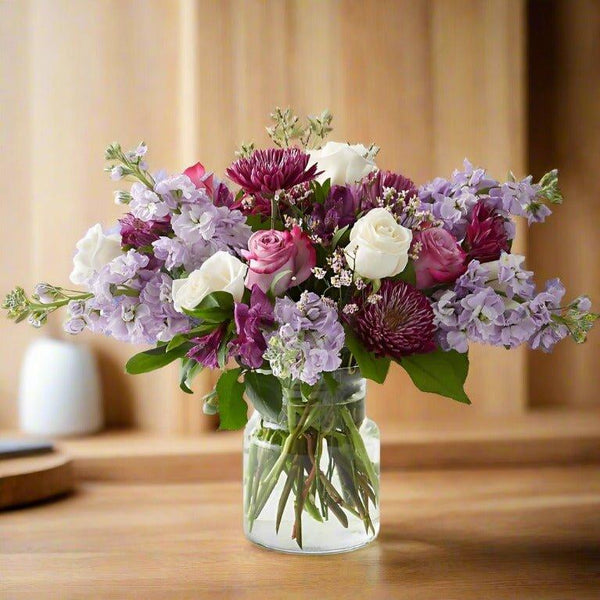 A bouquet of white, pink, and purple flowers in a glass vase.