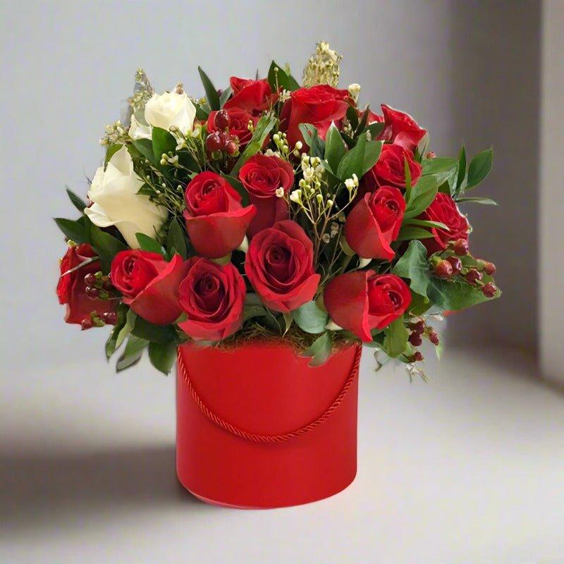 Bouquet of red and white roses in a red cylindrical vase.