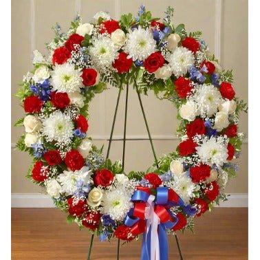 Red, White & Blue Standing Wreath  standing on an easel with red and white ribbon in the front of the arrangement 