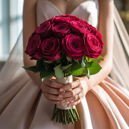 Bouquet of red roses held by a person in a light-colored dress.
