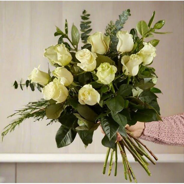 Bouquet of white roses with green leaves held by a hand