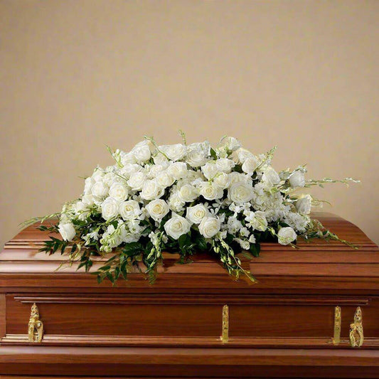 Full White Casket Roses floral arrangement for funeral service.